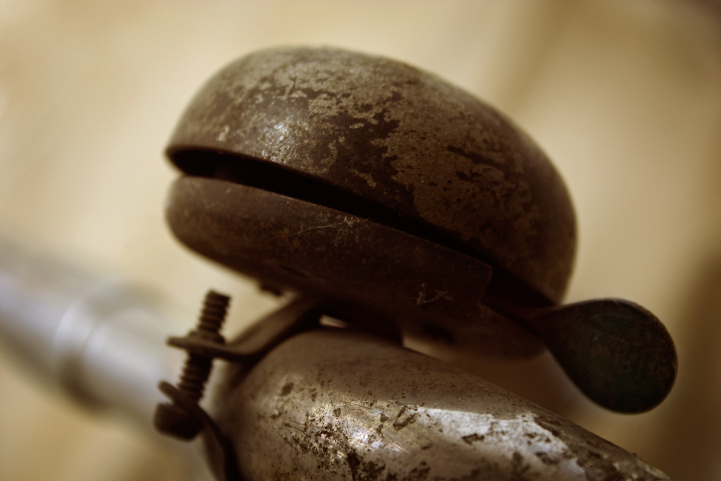 The bell of an old bicycle. The image has a narrow depth of field centered around the bell. The image is part of a series of photos of this bike, with each image concentrating on a different component.