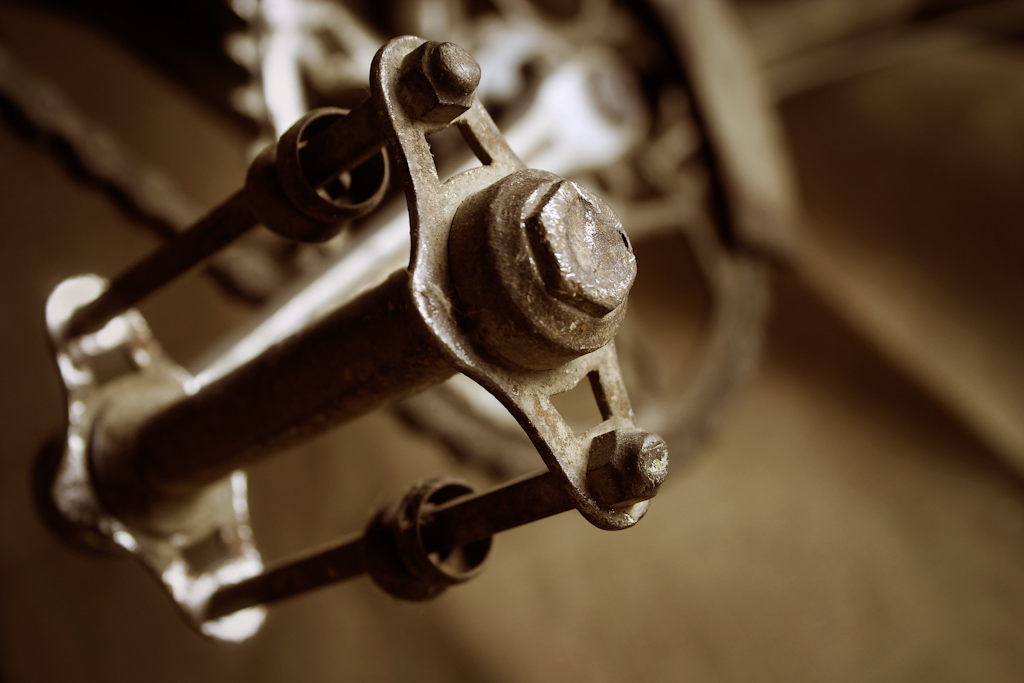 The pedal of an old rusted bicycle. The image has a narrow depth of field with the near end of the pedal in sharp focus. The image is part of a series of photos of this bike, with each image concentrating on a different component.