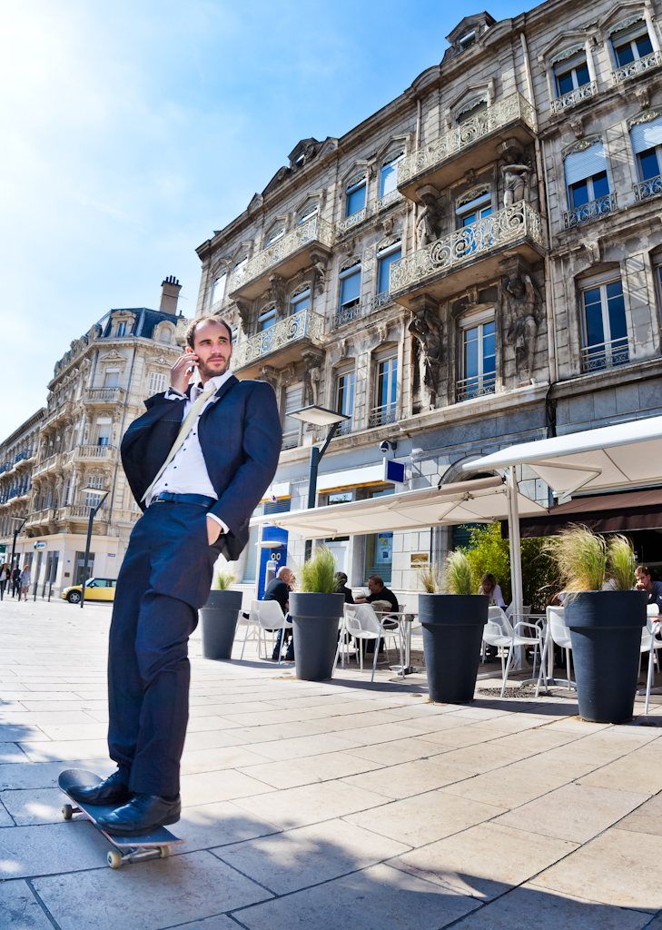 Man skateboarding in a suit through a French town. Commercial advertising style image.