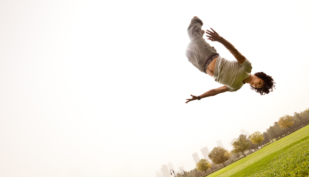 A acrobat somersaults in a park in Dubai.  Commercial advertising style image.